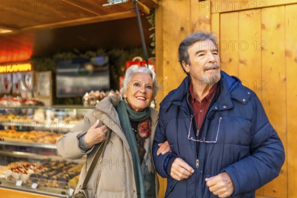 Happy senior couple strolling arm in arm at a traditional christmas market, enjoying the festive atmosphere and holiday cheer