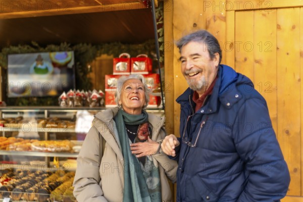 Cheerful senior couple smiling and enjoying the festive atmosphere at a christmas market in a winter city