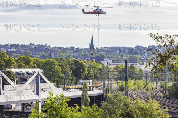 Track construction from the air. At Bad Cannstatt railway station, a transport helicopter transports 26 catenary masts to their destination. The masts, weighing up to 2.4 tonnes, were delivered by rail. The reason for this is to improve the infrastructure as part of the Stuttgart 21 project. Stuttgart, Baden-Württemberg, Germany