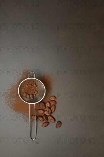 Kitchen sieve with cocoa powder, cocoa and cocoa beans