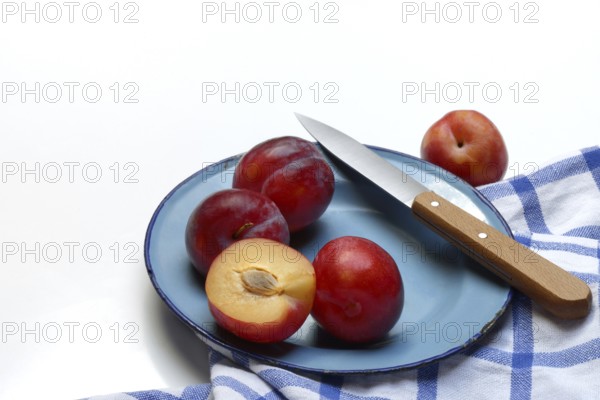 Red plums on plate with kitchen knife, Prunus domestica