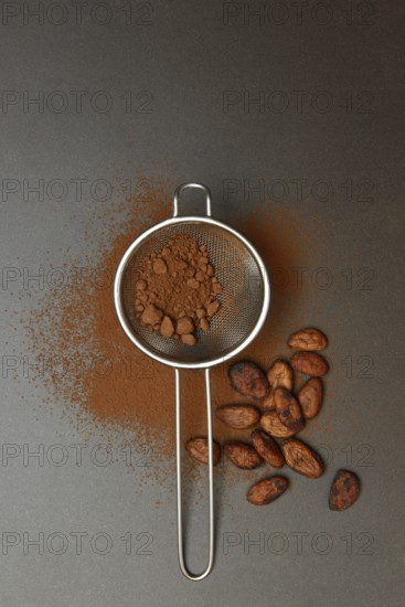 Kitchen sieve with cocoa powder, cocoa and cocoa beans
