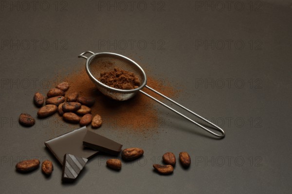 Kitchen sieve with cocoa powder and chocolate, cocoa and cocoa beans