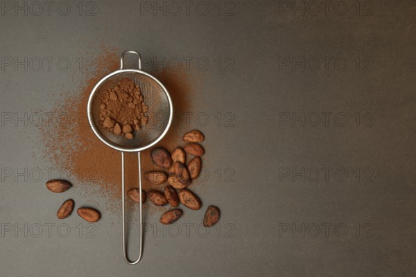 Kitchen sieve with cocoa powder, cocoa and cocoa beans