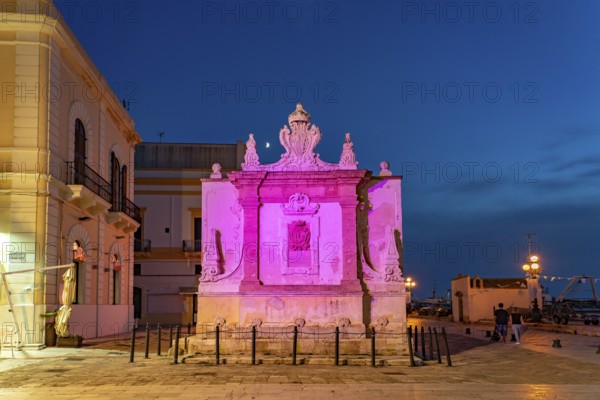 The colourfully illuminated Greek fountain Fontana Greca at dusk, Gallipoli, Apulia, Italy