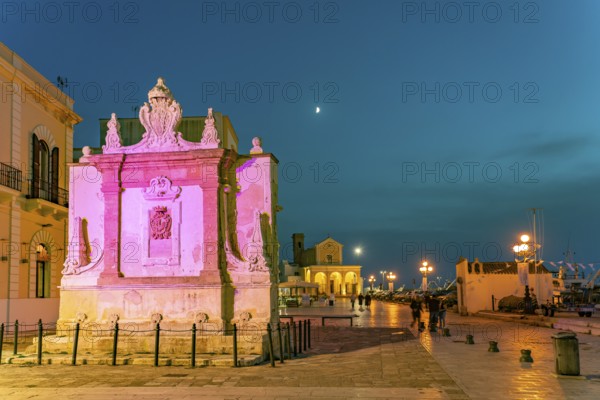 The colourfully illuminated Greek fountain Fontana Greca at dusk, Gallipoli, Apulia, Italy