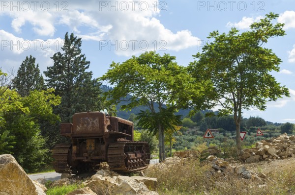 Old, heavily rusted bulldozer for road construction stands abandoned on rocks, industrial relic