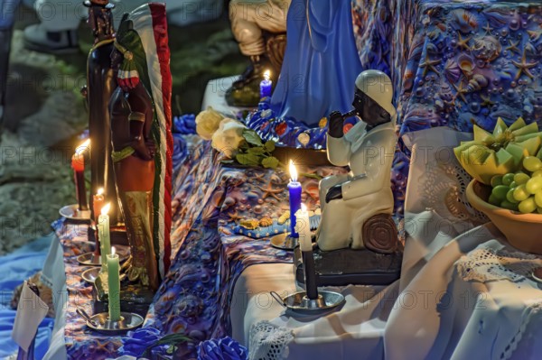 Altar with Umbanda deities and objects of worship lit by candles at night, Belo Horizonte, Minas Gerais, Brazil