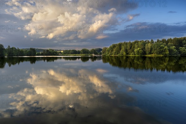 The Postfelden reservoir in the evening at the golden hour. Glowing clouds are reflected in the calm water. Höllbachtal, Postfelden, Rettenbach, Upper Palatinate, Bavaria, Germany