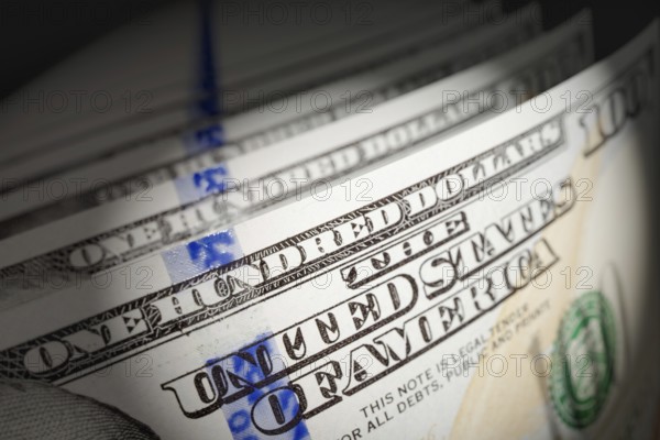 Spot lit abstract close-up angle of U.S. 100 dollar bills isolated on a black background