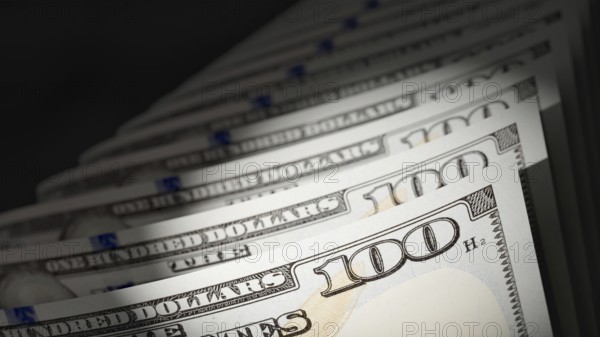 Spot lit abstract close-up angle of U.S. 100 dollar bills isolated on a black background