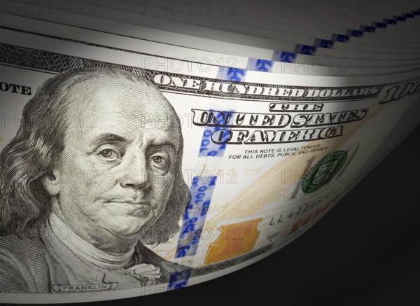 Spot lit abstract close-up angle of U.S. 100 dollar bills isolated on a black background