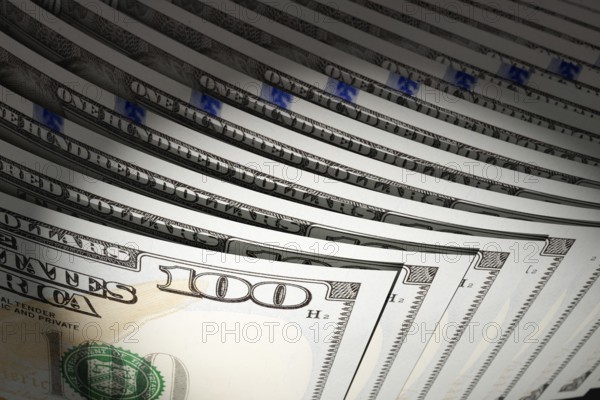 Spot lit abstract close-up angle of U.S. 100 dollar bills isolated on a black background