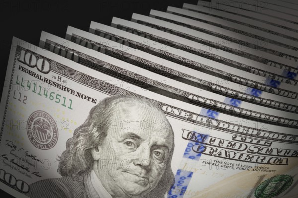 Spot lit abstract close-up angle of U.S. 100 dollar bills isolated on a black background