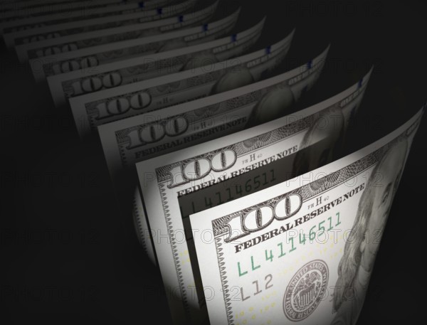 Spot lit abstract close-up angle of U.S. 100 dollar bills isolated on a black background
