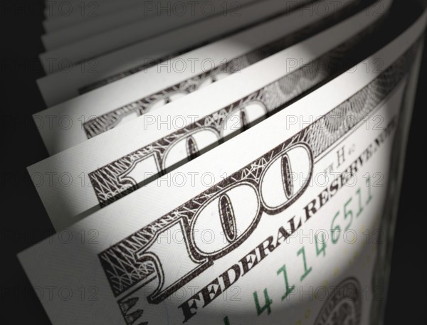 Spot lit abstract close-up angle of U.S. 100 dollar bills isolated on a black background