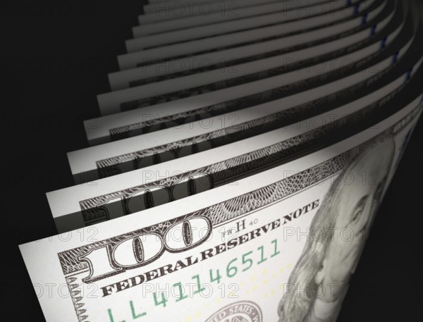 Spot lit abstract close-up angle of U.S. 100 dollar bills isolated on a black background