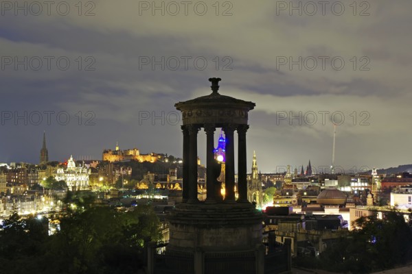 Night scene of Edinburgh with illuminated buildings and a historical monument in the foreground, Old Town, Calton Hill, Edinburgh, Scotland, United Kingdom
