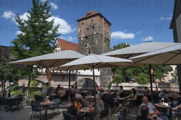 Historic water tower built around 1325, in front a café on the Pegnitz, Nuremberg, Middle Franconia, Bavaria, Germany