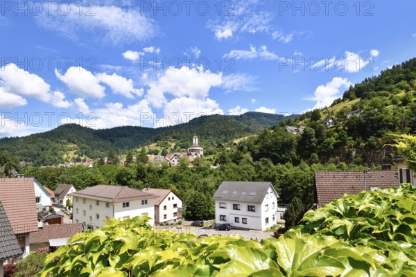 Forbach, Germany - July 12th 2025: Buildings surrounded by trees in Forbach. Scenic summer view of Black Forest town under blue sky