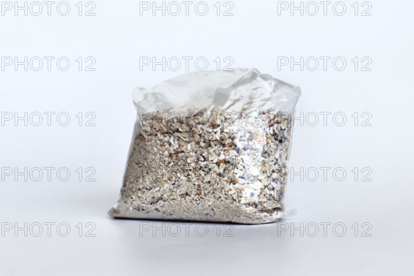 Small plastic bag containing ash of a pet cat after cremation on white background