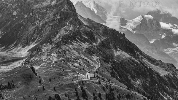 The historic Hotel Weisshorn below the Weisshorn mountain, behind the four-thousand-metre peaks and glaciers in clouds, drone shot, black and white image, Val d'Anniviers, Valais Alps, Canton Valais, Switzerland