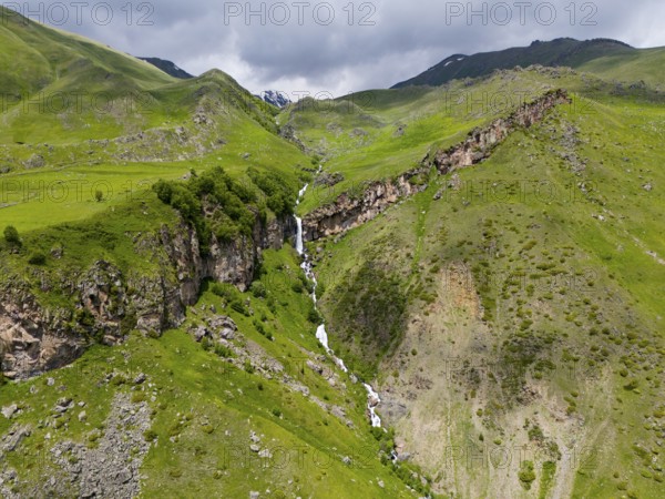 Waterfall cascading down the rocky mountain face, surrounded by green landscape, aerial view, Toti Waterfall or Arsha Waterfall, Arshistskhali River, Kazbegi, Qasbegi, Stepantsminda, Georgian Military Road, Mtskheta-Mtianeti Province, High Caucasus, Georgia