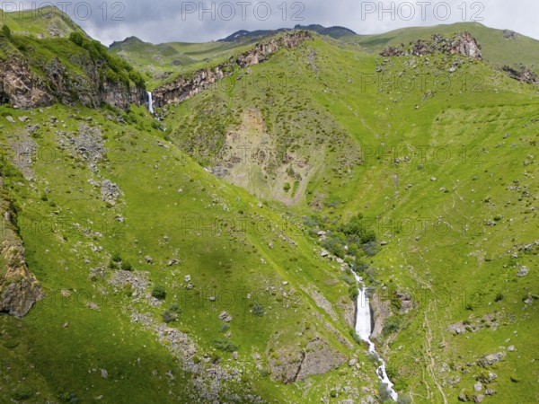 Waterfall in a green valley between rocky mountains, aerial view, Toti waterfall or Arsha waterfall, twin cascades, Arshistskhali river, Kazbegi, Qasbegi, Stepantsminda, Georgian Military Road, Mtskheta-Mtianeti province, High Caucasus, Georgia