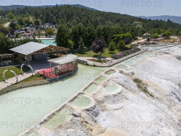 Panoramic view of limestone terraces next to a green park with a red platform, aerial view, Akkaya Travertines, Bolu Province, Turkey