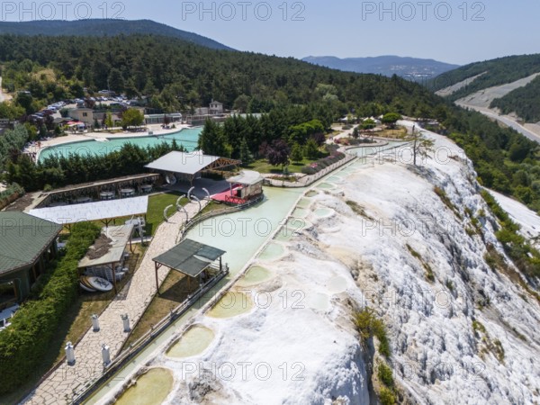 Thermal springs and buildings in a green landscape with limestone formations, aerial view, Akkaya Travertines, Bolu Province, Turkey