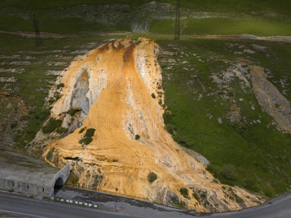 A hill with a distinctive orange rock formation next to a road with a bridge, aerial view, Bidara Travertine, Trawertin, Jvari Pass-Trawertin Natural Monument, Cross Pass, Mtskheta-Mtianeti Province, Georgia
