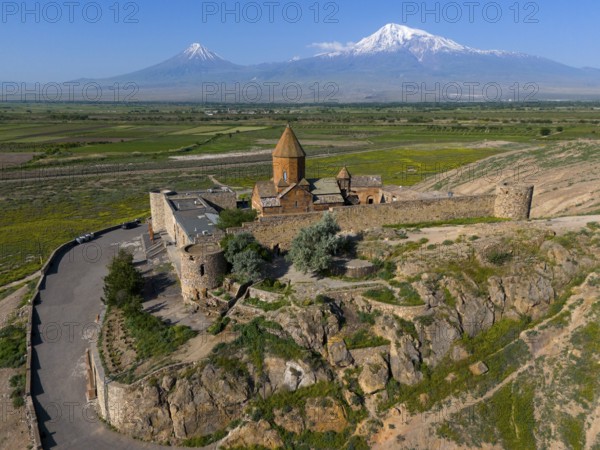 Historic church in a wide landscape in front of impressive mountain peaks under a clear sky, aerial view, Chor Wirap monastery, Chor Virap, deep dungeon, in the background Mount Ararat and Little Ararat, located in Turkey, Ararat province, Armenia