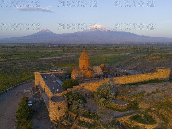Historic monastery with surrounding wall and view of Mount Ararat at sunrise, aerial view, Chor Wirap monastery, Chor Virap, deep dungeon, in the background Mount Ararat and Little Ararat, located in Turkey, Ararat province, Armenia
