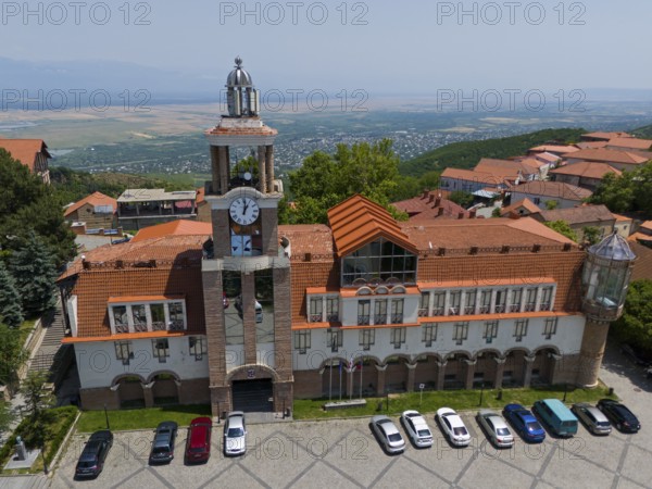 Large building with clock tower and surrounding traditional roofs on a slope, aerial view, town hall, Sighnaghi, Signagi, Kakheti Province, Greater Caucasus, Georgia, Near East