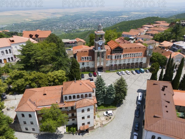 Square with a dominant tower and traditional buildings surrounded by green hills, aerial view, Sighnaghi, Signagi, Kakheti Province, Greater Caucasus, Georgia, Near East