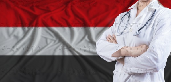 Doctor with crossed arms on Yemen flag. Yemeni health and care concept. Female doctor on Yemen flag