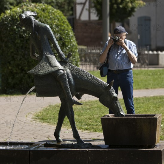 Man photographing the Münchhausen fountain by Bruno Schmitz with the halved horse, Bodenwerder, Weserbergland, Lower Saxony, Germany