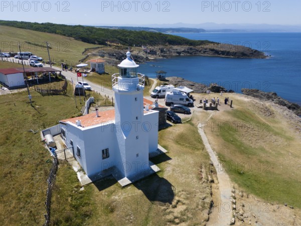 A lighthouse on the coast with mobile homes nearby, surrounded by meadow and rocks, the sea horizon in the background, aerial view, lighthouse, Inceburun, Inceburun is the northernmost point of Anatolia, Sinop province, Turkey