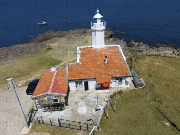 A lighthouse on a rocky coast with blue sky and sea, next to it a building with a terracotta roof, aerial view, lighthouse, Inceburun, Inceburun is the northernmost point of Anatolia, Sinop province, Turkey