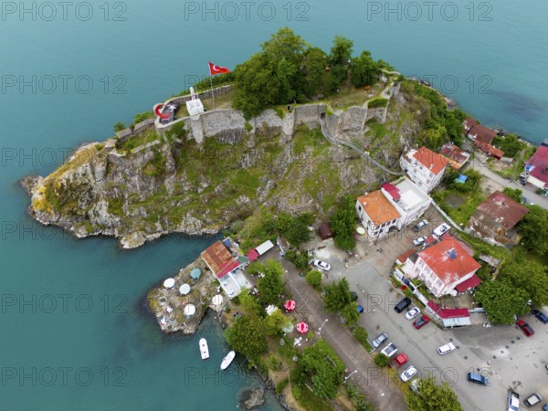 Aerial view of a castle by the sea with Turkish flag and surrounding buildings, aerial view, fortress, castle, Tirebolu, Giresun Province, Black Sea, Turkey