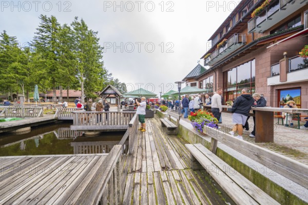 Animated dock area with people, wooden structures and neighbouring buildings, Mummelsee, Seebach, Ortenau district, Black Forest, Germany