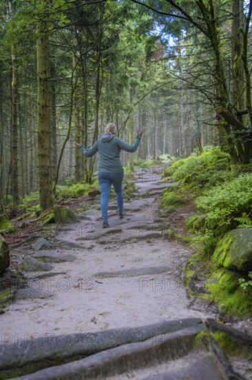 Woman walking along a forest path, surrounded by trees and moss, joyful movement, Mummelsee, Seebach, Ortenau District, Black Forest, Germany