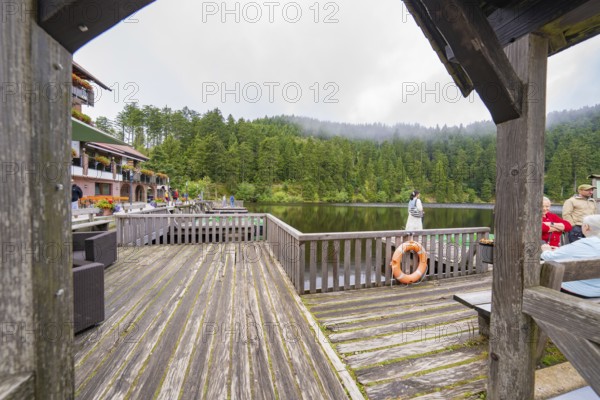 View of a lake from a wooden footbridge with buildings in the background, Mummelsee, Seebach, Ortenau district, Black Forest, Germany