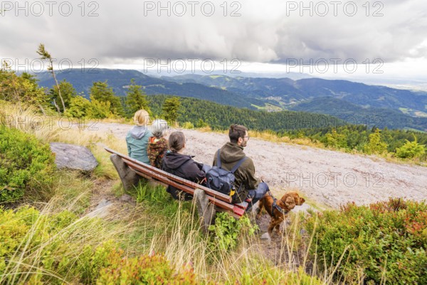 Group on a bench marvelling at the panorama over the mountain landscape with clouds in the sky, Mummelsee, Seebach, Ortenau district, Black Forest, Germany