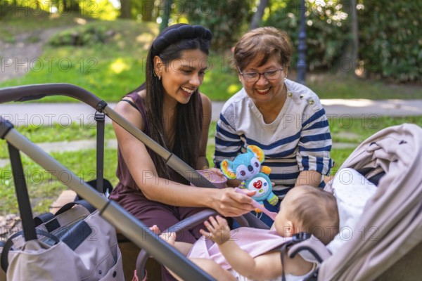 Grandmother, mother and baby girl enjoying time together at the park, mother feeding her baby solid food