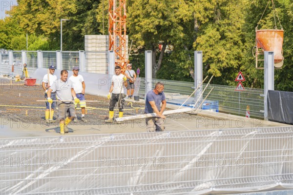 Group of construction workers on a building site with warning signs and a crane nearby, car park construction, Calw, Germany