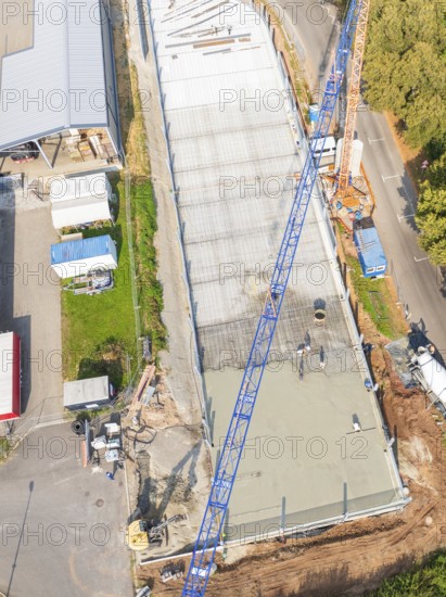 Aerial view of a construction site with blue crane and concrete surface next to a road, car park construction, Calw, Germany