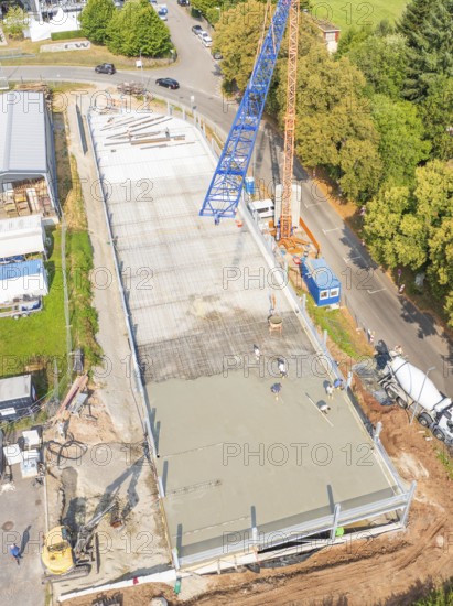 Top view of a construction site with crane and workers, surrounded by trees and roads, car park construction, Calw, Germany