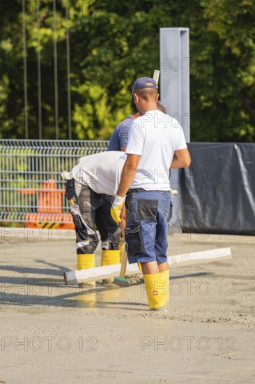 Close-up of construction workers concreting on a building site with safety equipment, car park construction, Calw, Germany