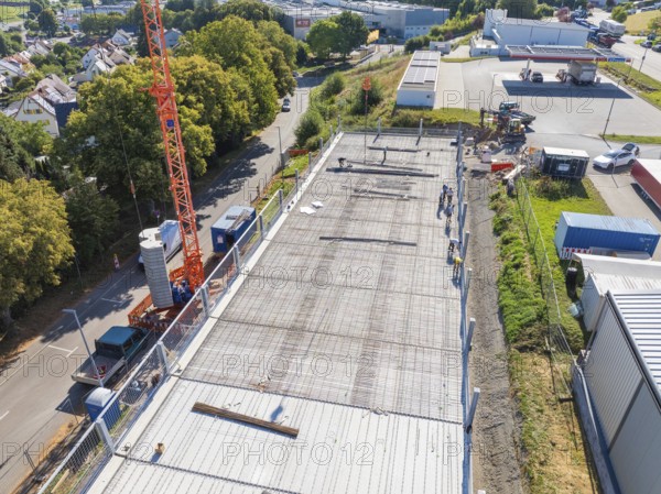 Crane over a construction site with workers and surrounding streetscape and landscape, car park construction, Calw, Germany